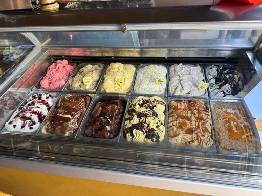 Eisvitrine mit verschiedenen Sorten, darunter Erdbeere, Schokolade und Vanille.
