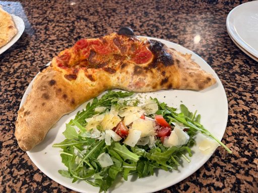 Calzone mit Tomatensauce und Käse, serviert mit frischem grünen Salat.