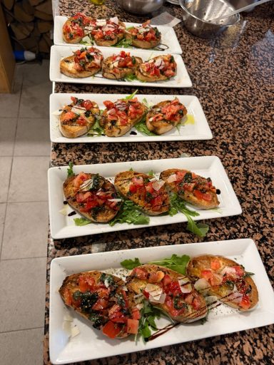 Gegrillte Austern mit Tomaten und Kräutern auf weißen Tellern angerichtet.