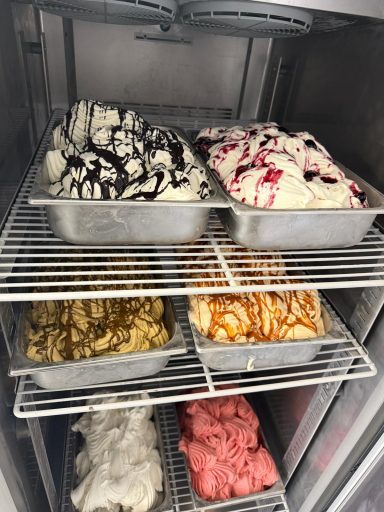 Verschiedene Eissorten in Behältern, hübsch dekoriert, in einer Gefriertruhe.