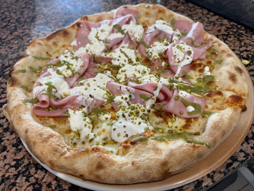 Pizza mit Schinken, Kräuter, Käse und einer knusprigen Kruste.